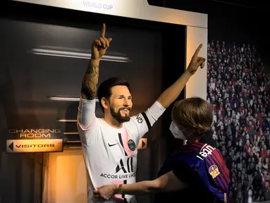 Seorang tim potret museum lilin Madame Tussauds Berlin, Karen Fries (kanan) memperbaiki jersey baru Paris Saint-Germain (PSG) pada patung lilin Lionel Messi di Berlin. (11/7/2021). Messi resmi bergabung dengan PSG dari Barcelona setelah menandatangani kontrak dua tahun. (AFP/Tobias Schwarz)
