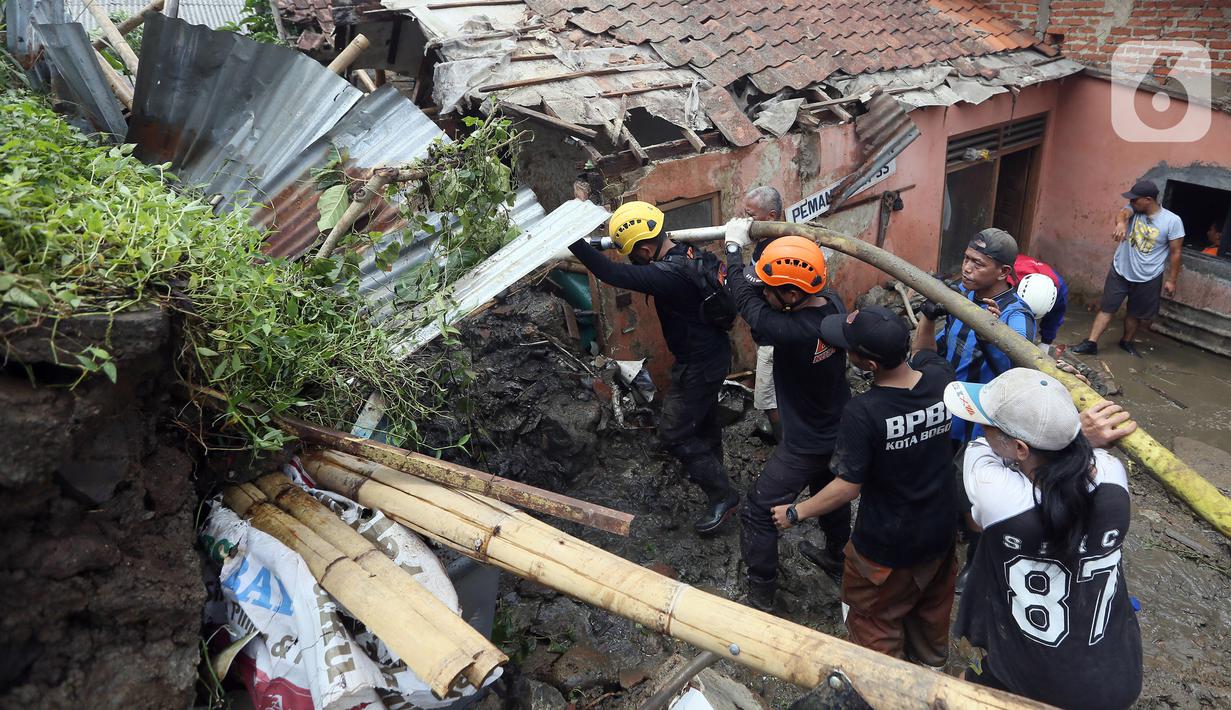 Petugas membersihkan material longsor pada areal pemancingan yang menyebabkan satu orang meninggal dunia di Gang Kepatihan, Kelurahan Kebon Kelapa, Kecamatan Bogor Tengah, Bogor, Jawa Barat, Rabu (12/10/2022). Longsor yang terjadi pada kemarin sore menyebabkan sembilan pemancing tertimbun tanah namun selamat dan seorang anggota kepolisian meninggal. (merdeka.com/Arie Basuki)