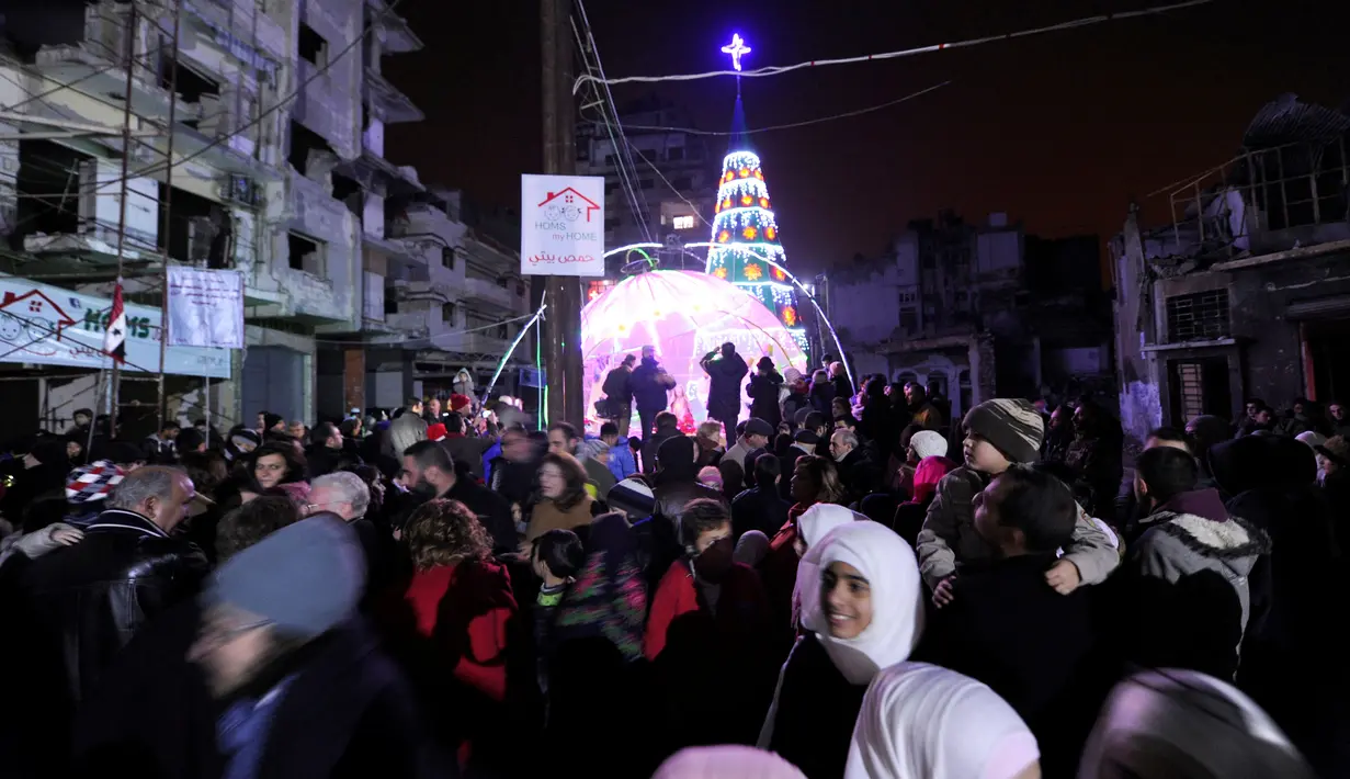 Sejumlah warga berkumpul saat perayaan malam Natal di kawasan Al-Hamidiyah kota tua Homs, Suriah, (24/12). Warga terpaksa merayakan malam Natal di tengah reruntuhan bangunan di daerah konflik tersebut. (REUTERS/Omar Sanadiki)