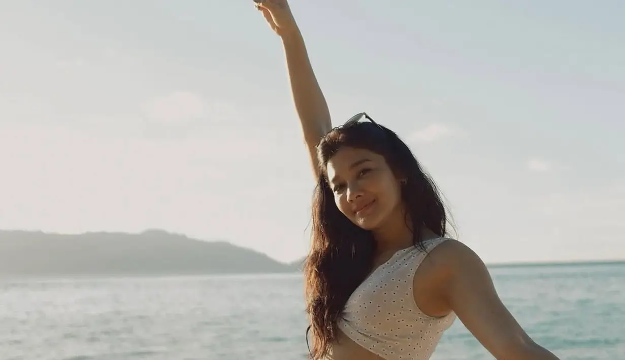 Naysila Mirdad menikmati pantai indah di Banda Naira. Terlihat ia mengenakan atasan crop top sleeveless bermotif dipadukan celana pendek coklat. Rambut panjangnya dibiarkan terurai dengan wajah terlihat bare face no makeup. [@naymirdad]