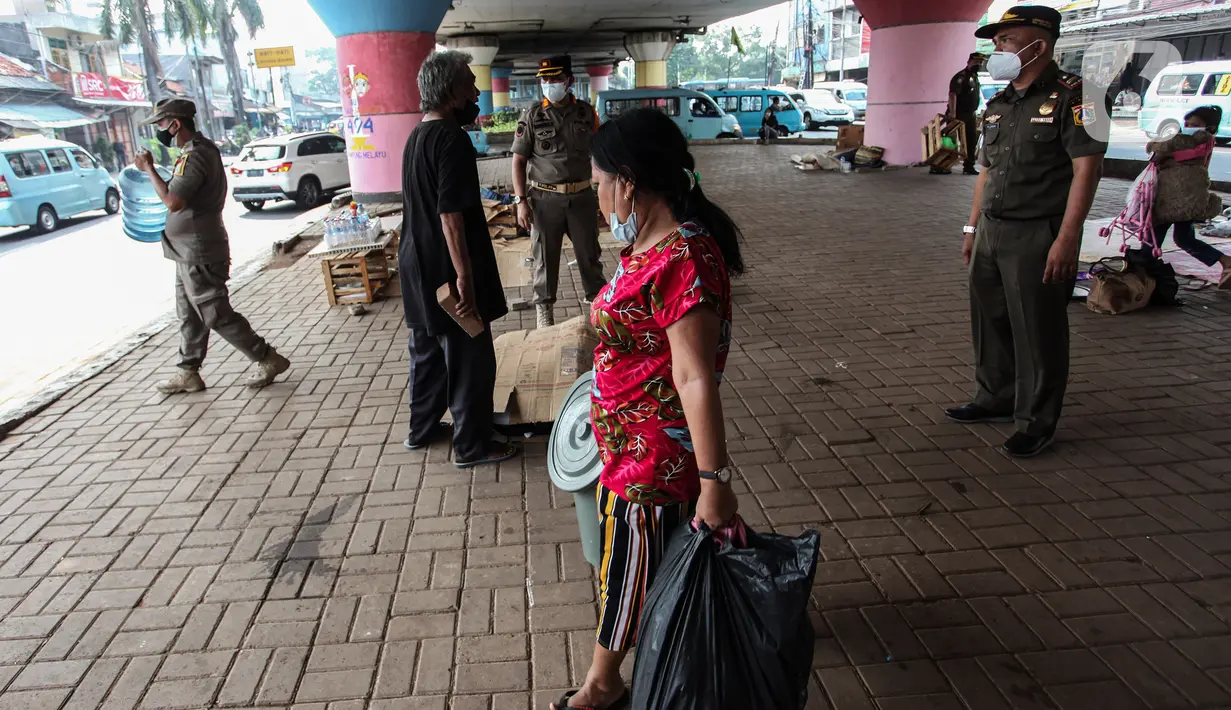 Seorang tunawisma membawa barang miliknya saat razia Satpol PP di bawah flyover Jatinegara, Jakarta Timur, Senin (19/7/2021). Razia ini merupakan upaya dari Kecamatan Jatinegara di kawasan Kampung Melayu untuk bersih dari tunawisma yang sering tidur dan berjualan.  (Liputan6.com/Johan Tallo)