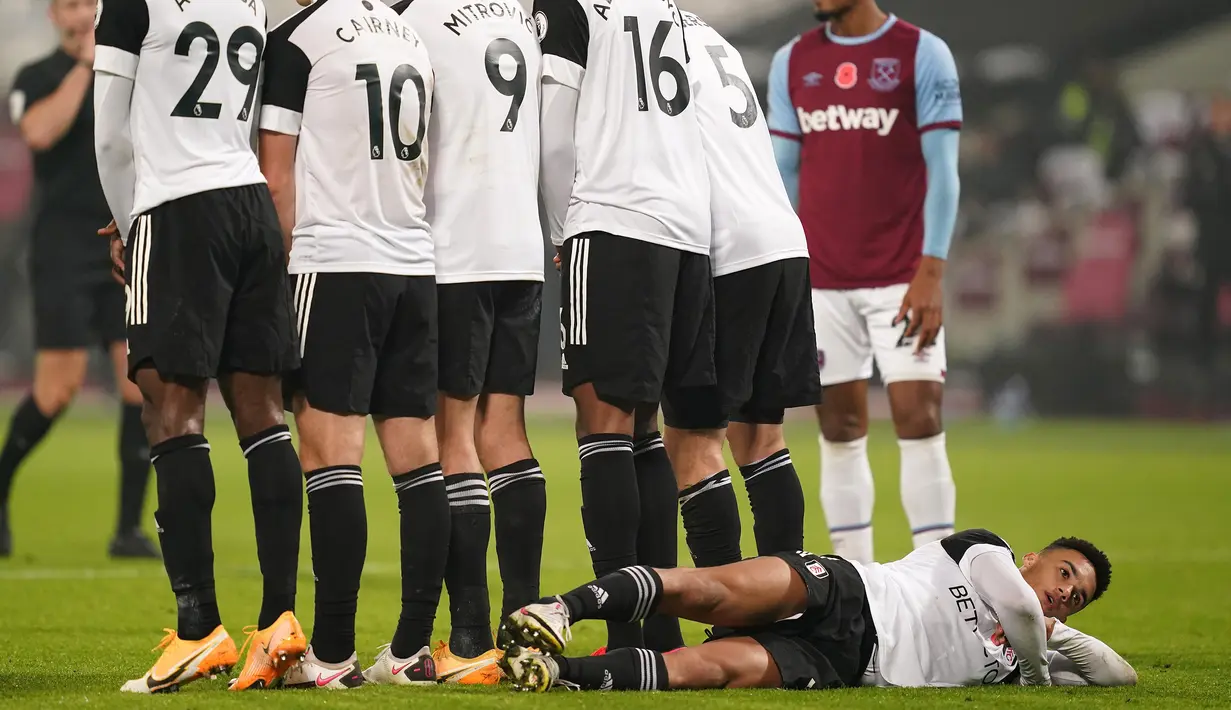 Bek Fulham, Antonee Robinson berbaring di belakang rekan-rekannya yang membuat pagar hidup untuk menjaga tendangan bebas pemain West Ham United dalam laga lanjutan Liga Inggris 2020/21 di London Stadium, Sabtu (7/11/2020). (AFP/John Walton/Pool)