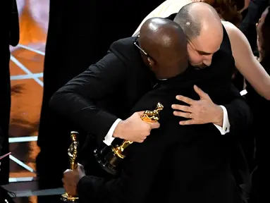 Produser La La Land, Jordan Horowitz (kiri) berpelukan dengan sutradara Moonlight, Barry Jenkins usai kesalahan pembacaan pemenang film terbaik di ajang Oscar 2017 di Hollywood, California, AS (26/2). (AFP/Getty Images/Kevin Winter)
