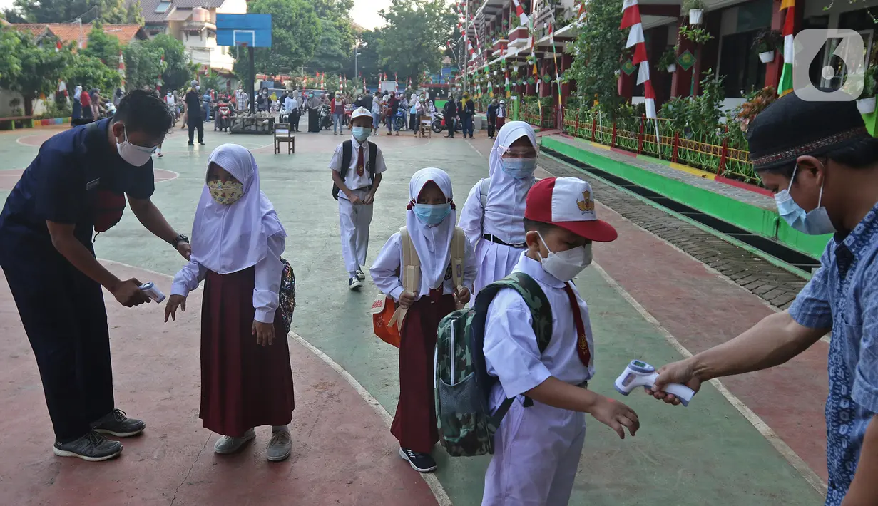 Petugas mengecek suhu badan para siswa setibanya di SDN 05 Kalisari, Jakarta, Senin (30/8/2021). Pemprov DKI menggelar pembelajaran tatap muka di tengah pandemi covid-19 mulai 30 Agustus 2021 secara terbatas dengan kapasitas 50 persen pada setiap satuan pendidikan. (Liputan6.com/Herman Zakharia)