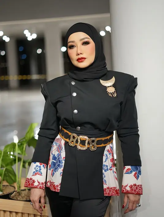 Aksen belt dan bros sebagai pemanis menambah impresi mewah pada penampilan penyanyi 49 tahun itu. Disempurnakan dengan pulasan makeup flawless dan tatanan hijab yang diikat rapi ke belakang. [@rezaartameviaofficial].
