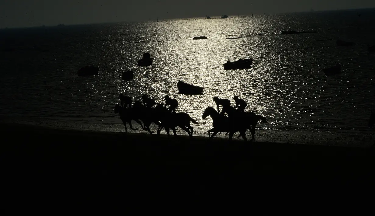 Sileut peserta lomba pacuan kuda pantai tahunan di Sanlucar de Barrameda, dekat Cadiz, Spanyol (17/8). Dalam perlombaan ini peserta harus beradu cepat melintasi jalur pacu sepanjang 1400 meter. (AFP Photo/Cristina Quicler)