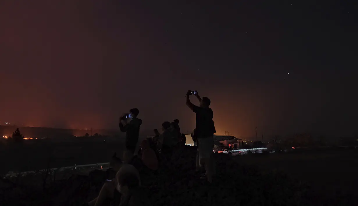 Orang-orang melihat ke gunung berapi Cumbre Vieja yang terus meletus di pulau Canary La Palma, Spanyol pada Sabtu (16/10/2021). Para pejabat mengatakan tidak ada tanda-tanda bahwa letusan gunung berapi di pulau La Palma Spanyol akan segera berakhir, satu bulan setelah dimulai. (AP Photo/Daniel Roca)