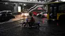 Pengendara berkendara melalui jalan yang banjir saat hujan deras di Bangkok (23/9/2020). (AFP/Mladen Antonov)