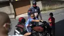 Seorang anak duduk di atas sepeda motor Everaldo Pinto, petugas polisi militer yang berkostum superhero Captain America di Petropolis, Rio de Janeiro, Brasil, Kamis (15/4/2021). Pinto memberitahu anak-anak tentang perlunya melindungi diri dari virus corona. (AP Photo/Silvia Izquierdo)