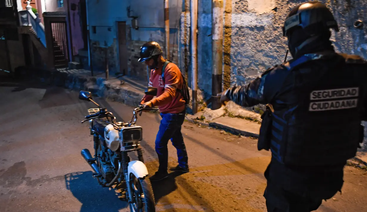 Anggota polisi bersiap menggeledah warga dalam operasi di tengah pandemi COVID-19 di Los Teques, negara bagian Miranda, Venezuela, 20 Maret 2021. Di Miranda ada pembatasan keluar sejak pukul 18.00 dan perintah penutupan toko pada pukul 16.00 di tengah gelombang kedua pandemi. (Federico PARRA/AFP)