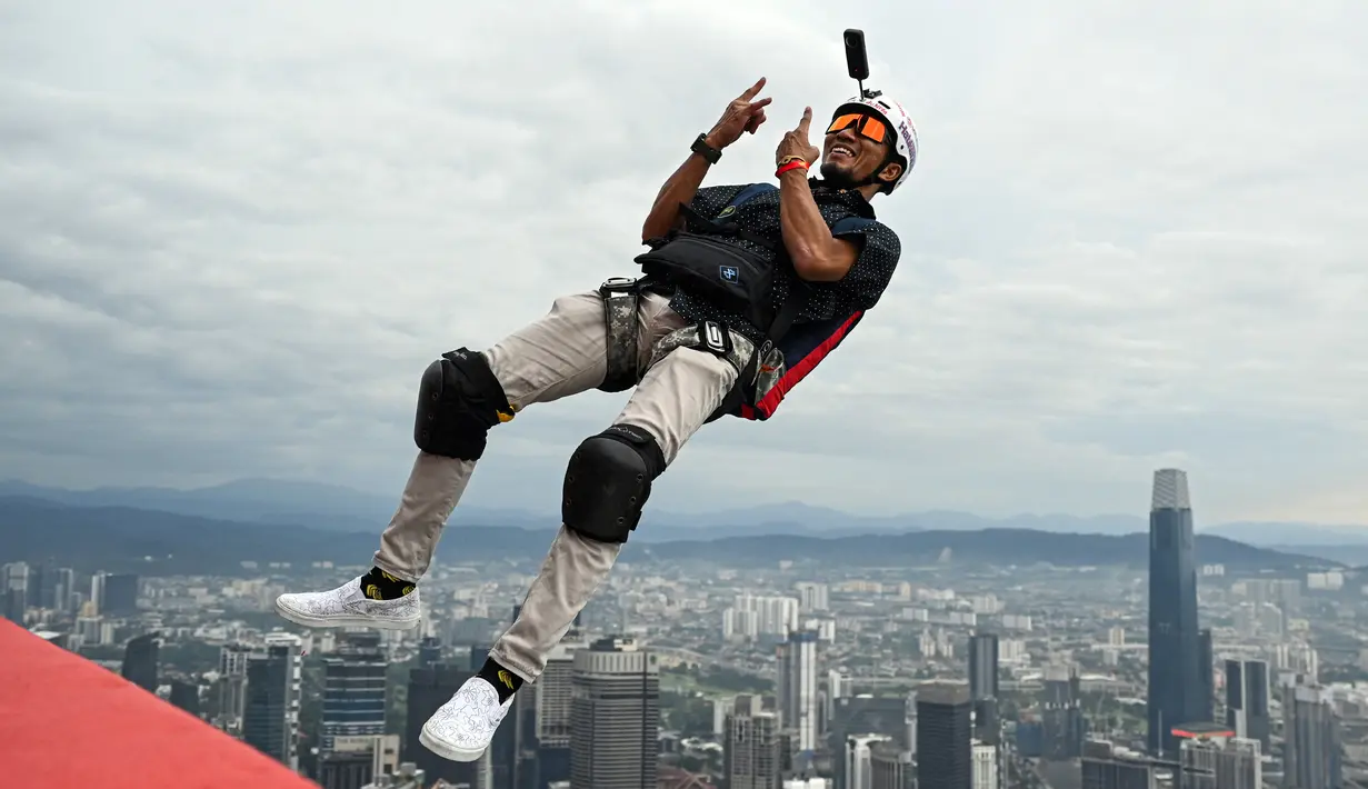 Penerjun Malaysia Adi Khirman Marji melompat dari dek terbuka Menara Kuala Lumpur saat International Tower Jump, Kuala Lumpur, Malaysia, 3 Februari 2023. Lebih dari 100 penerjun melompat dari Menara Kuala Lumpur setinggi 300 meter yang terkenal tersebut. (MOHD RASFAN/AFP)