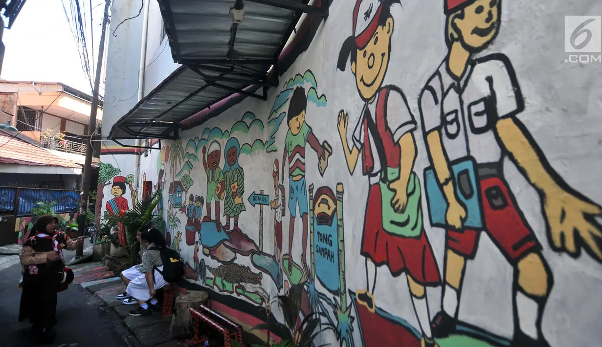 Anak sekolah melintas di depan lukisan tembok atau mural yang menghiasi gang di RT 13 RW 06, Jembatan Lima, Jakarta, Kamis (10/1). Pembuatan mural itu dimaksudkan agar lingkungan menjadi lebih tertata dan indah. (Merdeka.com/Iqbal Nugroho)