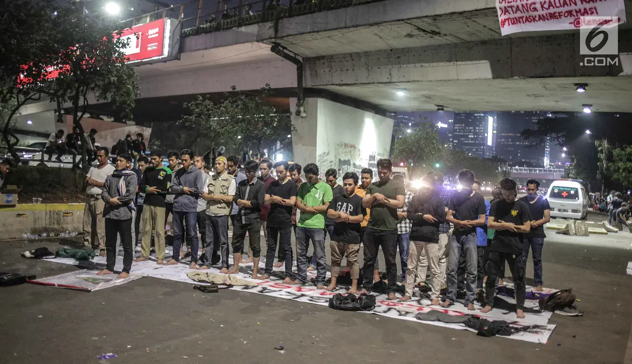 Massa dari Badan Eksekutif Mahasiswa Seluruh Indonesia (BEM SI) melakukan salat magrib disela unjuk rasa di depan gedung DPR/MPR RI, Jakarta, Selasa (1/10/2019). Di sela-sela agenda pelantikan anggota baru DPR RI 2019-2024, gelombang mahasiswa kembali menggelar demo. (Liputan6.com/Faizal Fanani)