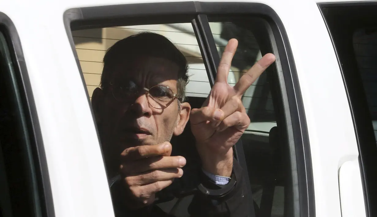 Pembajak pesawat EgyptAir, Seif Eldin Mustafa mengacungkan dua jarinya saat berada di dalam mobil tahanan di sebuah pengadilan di Larnaca, Siprus, Rabu (30/3). Seif Eldin Mustafa menyerahkan diri dan membebaskan 5 sandera. (REUTERS/Yiannis Kourtoglou)