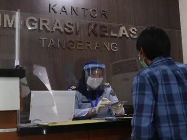 Petugas dengan mengenakan masker dan pelindung wajah melayani pemohon paspor di Kantor Imigrasi Kelas I Non TPI Tangerang, Senin (15/6/2020). Memasuki masa tatanan normal baru, pelayanan keimigrasian untuk warga mulai aktif kembali dengan menerapkan protokol kesehatan. (Liputan6.com/Angga Yuniar)