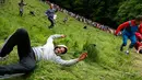 Ekspresi peserta yang jatuh saat mengejar gulungan keju dalam kompetisi Cheese Rolling di Brockworth, Gloucestershire, Inggris, 30 Mei 2016. Persaingan dimulai setelah keju yang berbentuk seperti roda digelindingkan dari puncak bukit. (Adrian DENNIS/AFP)