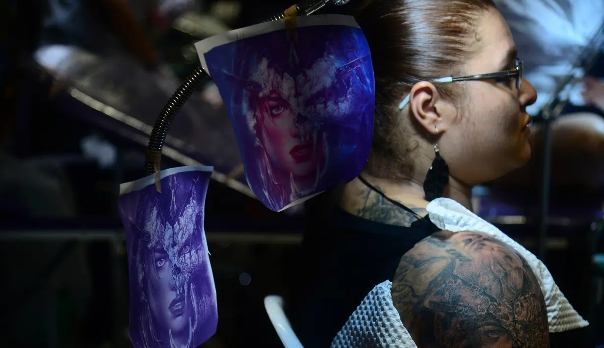 Seorang wanita dibuatkan tato di salah satu stan saat mengunjungi Expotattoo Colombia 2016 di Medellin, Kolombia, (16/7). Sejumlah wanita tampak antusias untuk mentato tubuhnya di festival tato terbesar di negara tersebut. (AFP PHOTO/RAUL Arboleda)