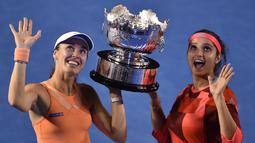 Martina Hingis (kiri) dan Sania Mirza berpose dengan trofi juara ganda putri setelah mengalahkan Lucie Hradecka dan Andrea Hlavackova di final tenis Australia Terbuka 2016 di Melbourne Park, Australia, (29/1/2016). (AFP/Peter Parks)