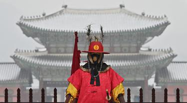 Seorang 'penjaga istana' berdiri untuk turis di depan Istana Gyeongbokgung yang tertutup salju di pusat kota Seoul (19/1/2022). Pihak berwenang di Seoul dan daerah sekitarnya pada Rabu (19/1) tetap waspada karena wilayah ibu kota diperkirakan akan turun salju lebat sepanjang hari. (AFP/Jung Yeon-je)