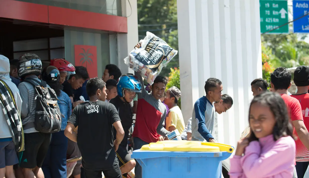 Warga menjarah kebutuhan pokok dari toko swalayan setelah gempa kuat dan tsunami mengguncang Kota Palu di Sulawesi Tengah, Minggu (30/9). Warga terpaksa mengambil karena mereka juga membutuhkan makanan dan air bersih. (AFP PHOTO/BAY ISMOYO)