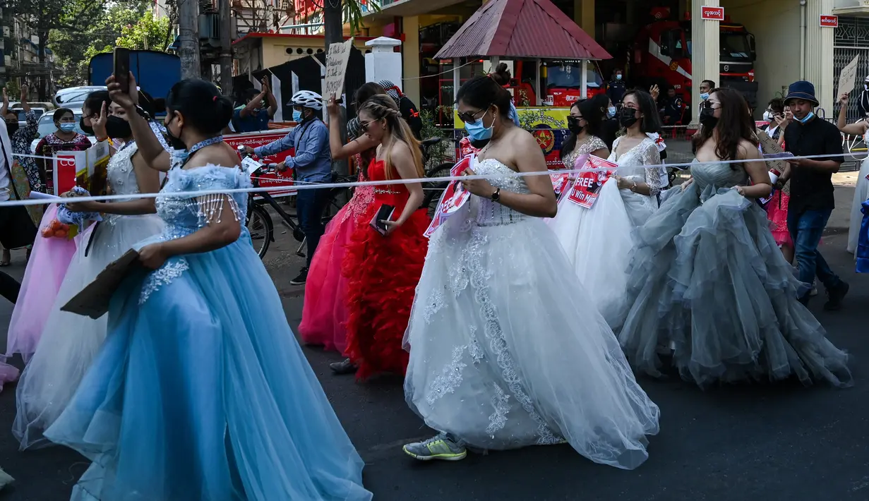 Sejumlah wanita Myanmar memakai gaun pengantin memegang plakat selama demonstrasi menentang kudeta militer 1 Februari di Yangon (10/2/2021).  aksi protes terjadi selama empat hari berturut-turut untuk menentang kudeta yang menggulingkan pemimpin sipil Aung San Suu Kyi. (AFP/ Ye Aung Thu)