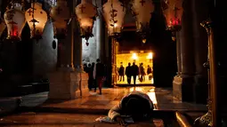 Seorang jemaat Kristen berdoa di batu pengurapan setelah tiga hari penutupan Gereja Makam Kudus di Yerusalem, Rabu (28/2). Penutupan oleh pemimpin gereja karena memprotes kebijakan pajak Israel dan UU yang diusulkan. (THOMAS COEX/AFP)