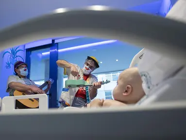 Badut dari LSM Media Sunrise (Senyuman Medis) tampil untuk bayi di sayap anak-anak Rumah Sakit Son Espases, Palma de Mallorca, Spanyol, 8 Maret 2021. (JAIME REINA/AFP)