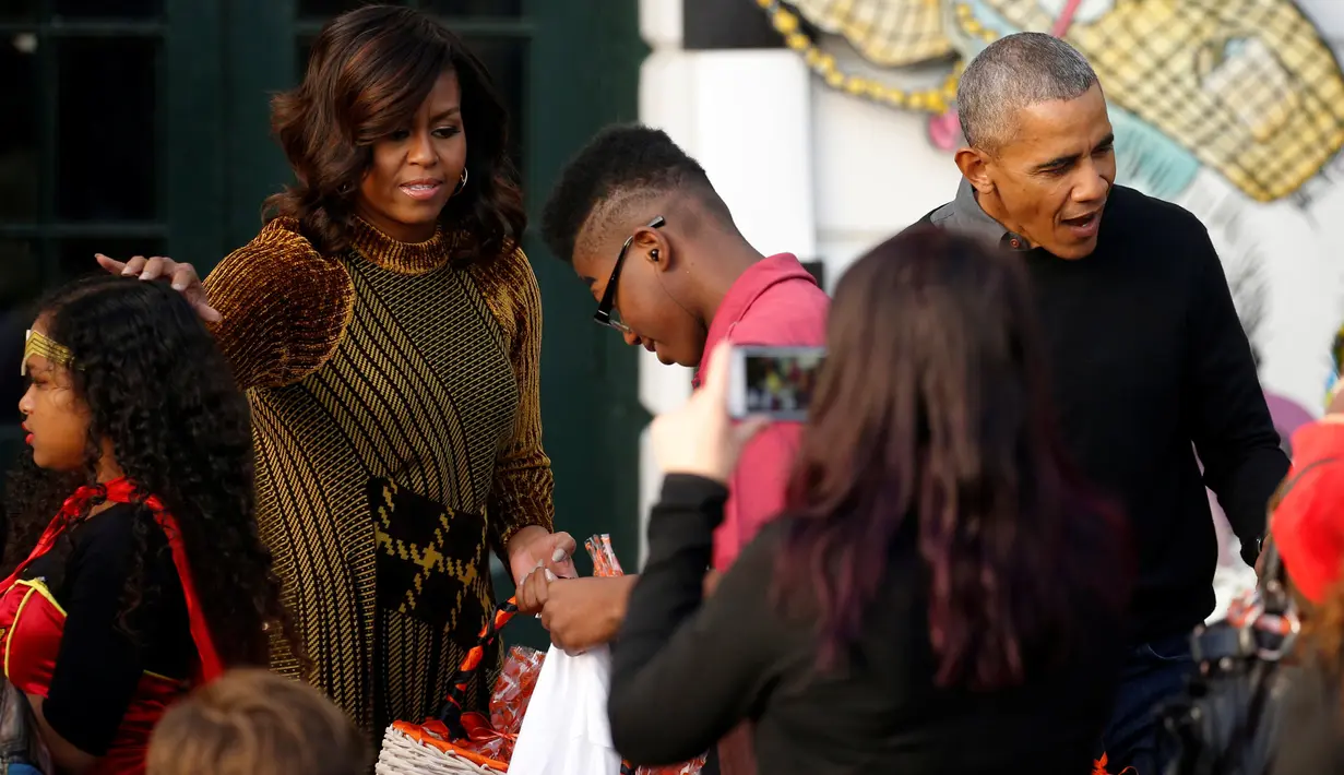 Presiden AS, Barack Obama dan ibu negara Michelle Obama membagikan coklat dan permen ke anak-anak dari Portico Selatan dan keluarga militer saat merayakan Halloween di Gedung Putih, Washington, Senin (31/10). (REUTERS / Jonathan Ernst)
