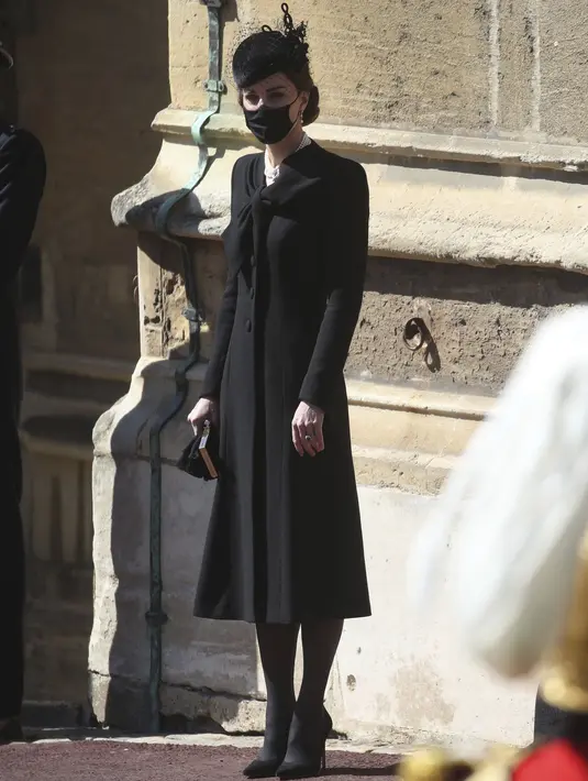 Kate Middletone, Duchess of Cambridge berdiri menjelang pemakaman Pangeran Philip di kastil Windsor, Inggris (17/4/2021). Kate Middletone, Duchess of Cambridge tampil memesona dengan busana dan masker hitam. (Steve Parsons/Pool via AP)