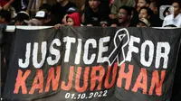 Pendukung timnas Indonesia membentang spanduk bertuliskan “Justice for Kanjuruhan” saat menyaksikan laga kualifikasi Grup A Piala AFF 2022 antara Indonesia melawan Kamboja di di Stadion Utama Gelora Bung Karno, Jakarta, Jumat (23/12/2022). Mereka menyuarakan pengusutan tuntas kasus atas Tragedi Kanjuruhan yang terjadi pada awal Oktober 2022 lalu. (Liputan6.com/Helmi Fithriansyah)