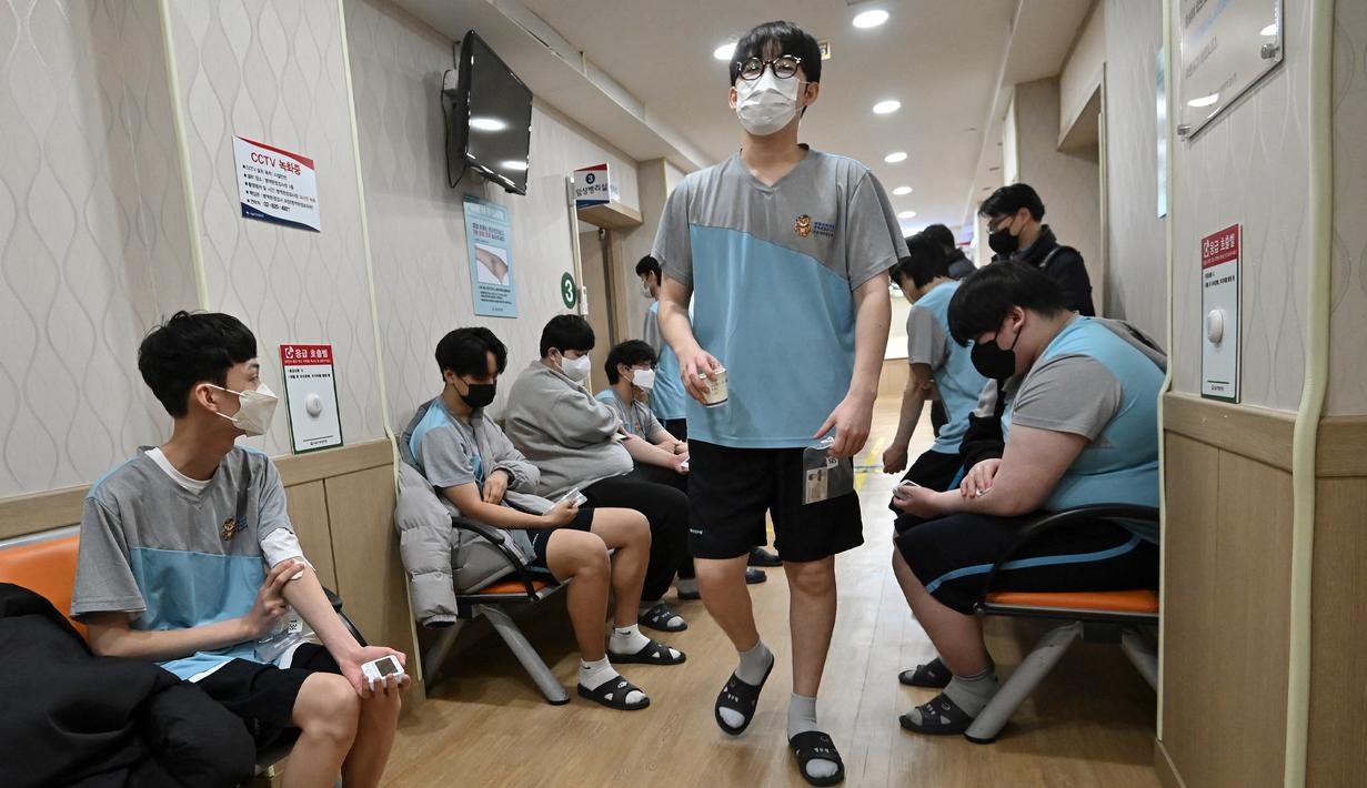 Sejumlah pemuda Korea Selatan menekan lengan mereka setelah melakukan tes darah saat pemeriksaan medis untuk wajib militer di Administrasi Tenaga Kerja Militer Regional Seoul, Seoul, Korea Selatan, Rabu (1/2/2023). Beberapa minggu awal mengikuti wajib militer, mereka diberikan pelatihan dasar militer meliputi latihan fisik seperti push up, marching, sampai latihan menembak. (Jung Yeon-je/AFP)