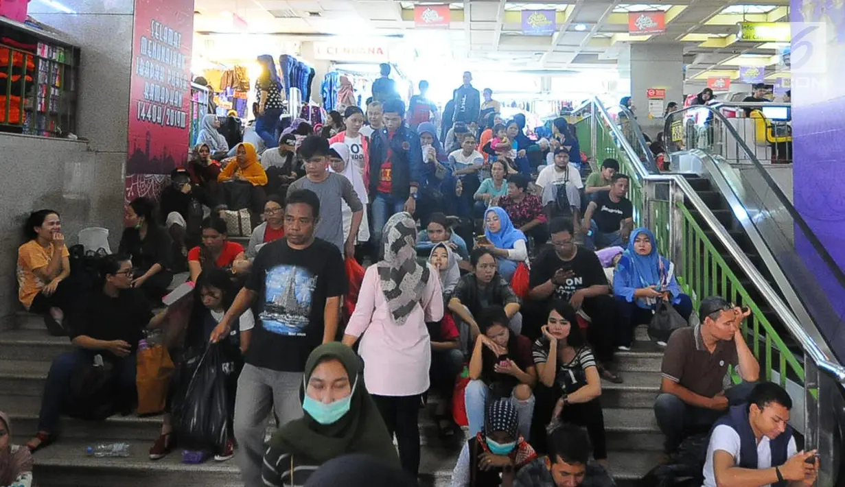 Sejumlah warga beristirahat usai berbelanja di pasar Tanah Abang, Jakarta, Minggu (26/5/2019). Jelang lebaran masyarakat mulai memadati pusat perbelanjaan untuk membeli kebutuhan saat Hari Raya Idul Fitri. (Liputan6.com/Angga Yuniar)