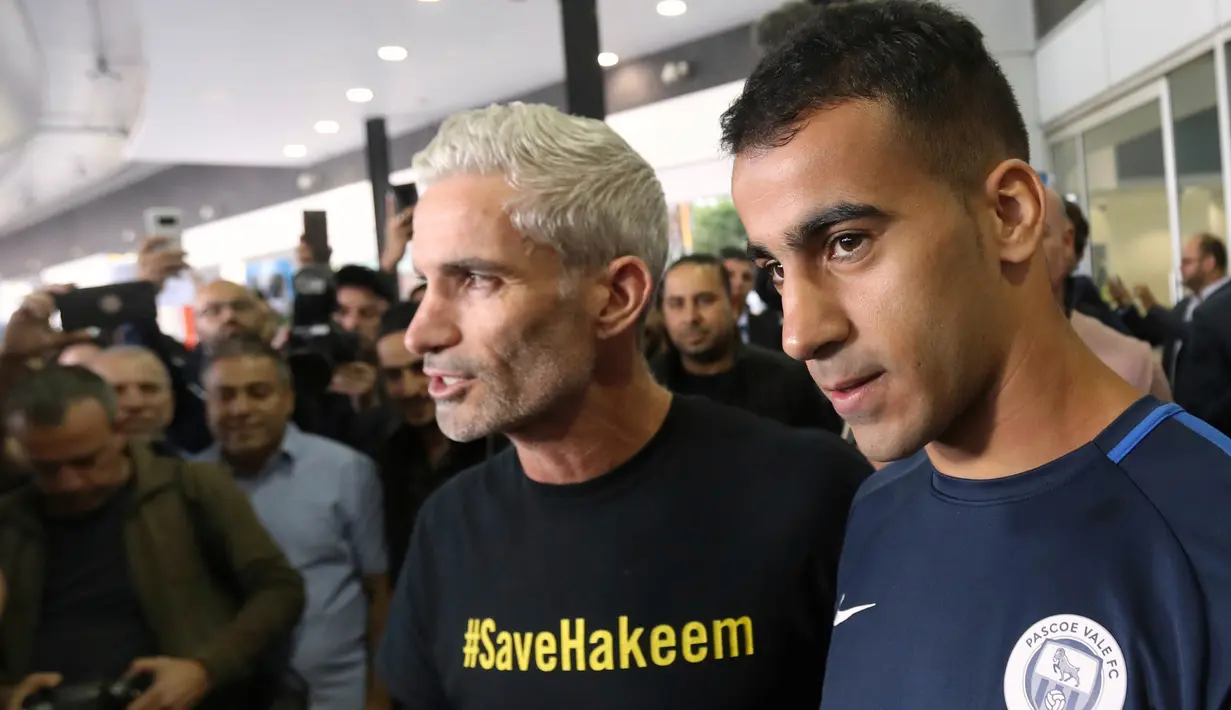Pemain sepakbola, Hakeem al-Araibi ditemani mantan pemain Socceroo Craig Foster setibanya di bandara Melbourne, Selasa (12/2). Hakeem dibebaskan dari penjara Thailand tempat ia ditahan menunggu sidang ekstradisi. (David Crosling/AAP Image via AP)