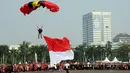 Dengan membawa Sang Merah Putih berukuran besar, salah satu peterjun bersiap mendarat di kawasan Tugu Monas, Jakarta, (31/8/2014). (Liputan6.com/Helmi Fithriansyah)