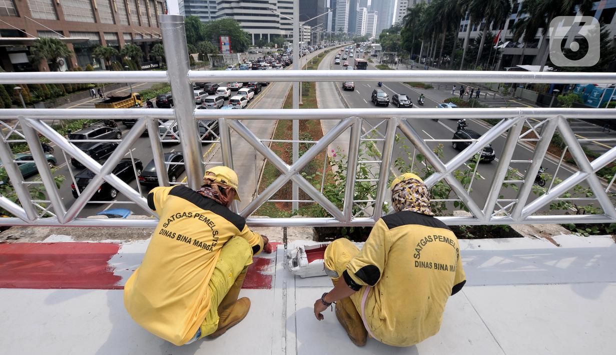 Petugas Bina Marga DKI Jakarta mengecat jembatan penyeberangan orang (JPO) yang tidak beratap di jalan Sudirman, Rabu (6/11/2019). Pemprov DKI melalui Dinas Bina Marga mencopot atap JPO Sudirman agar pejalan kaki dapat menikmati pemandangan gedung-gedung pencakar langit. (merdeka.com/Iqbal Nugroho)