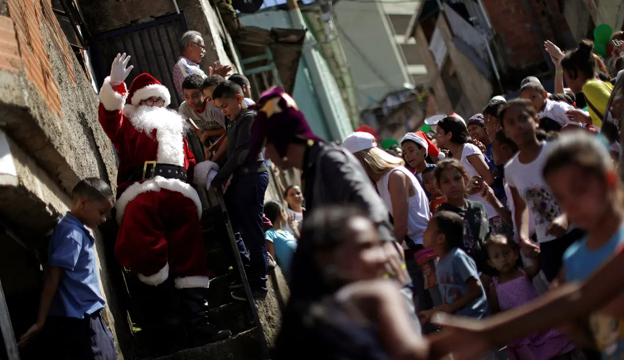 Puluhan anak-anak menyambut Santa Claus saat kunjungannya ke kawasan kumuh Petare di Caracas, Venezuela (11/12). Kunjungan Santa Claus ini untuk menghibur anak-anak dalam menyambut datangnya natal. (Reuters/Ueslei Marcelino)
