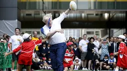 Walikota London Boris Johnson (kanan) asik bermain dengan anak - anak sekolah dasar di sebuah lapangan mini, Tokyo, Jepang, Kamis (15/10/2015).  Boris bermain Rugby untuk menyambut Jepang sebagai tuan rumah Piala Dunia Rugby 2019. (REUTERS/Issei Kato) 