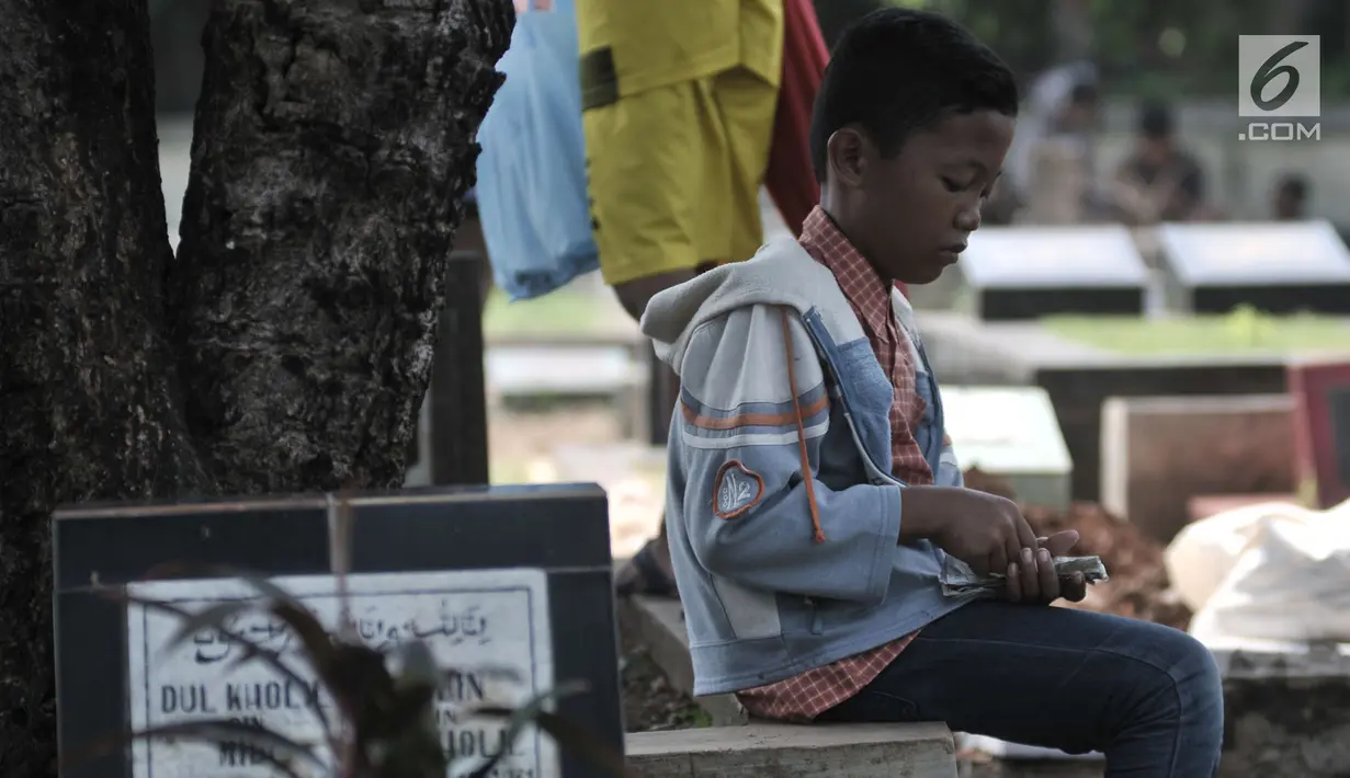 Seorang anak menghitung uang hasil jasa membersihkan makam di TPU Penggilingan, Pulogadung, Jakarta, Kamis (10/5). Tradisi ziarah jelang Ramadan menjadi berkah bagi anak-anak pembersih makam atau biasa dikenal 'Ngoret'. (Merdeka.com/Iqbal S. Nugroho)