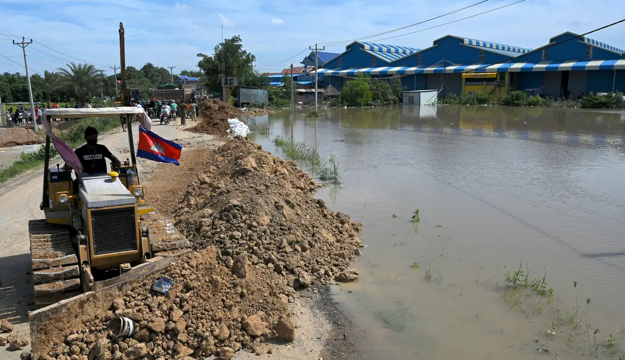 Buldoser mendorong tanah mencaegah kenaikan air banjir di Phnom Penh, Kamboja (26/10/2021). Kementerian Sumber Daya Air dan Meteorologi telah mengeluarkan pemberitahuan pada hari Senin tentang situasi cuaca, mengkonfirmasikan risiko banjir di 14 ibu kota dan provinsi Kamboja. (AFP/Tang Chhin Sothy)