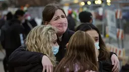 Warga saling menghibur di sepanjang pagar yang dipasang di sekitar tempat parkir tempat penembakan massal terjadi di toko King Soopers di Boulder, Colorado (23/3/2021). (AP Photo/David Zalubowski)