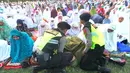 Jemaah perempuan yang pingsan langsung dievakuasi dua petugas polisi. (merdeka.com/Arie Basuki)