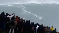 Penonton menyaksikan peselancar Jerman Sebastian Steudtner saat berusaha menaklukkan ombak Praia do Norte atau Pantai Utara di Nazare, Portugal, Selasa (11/2/2020). Praia do Norte menjadi tempat uji nyali peselancar dunia karena ombaknya yang bisa mencapai 30 meter. (AP Photo/Armando Franca)