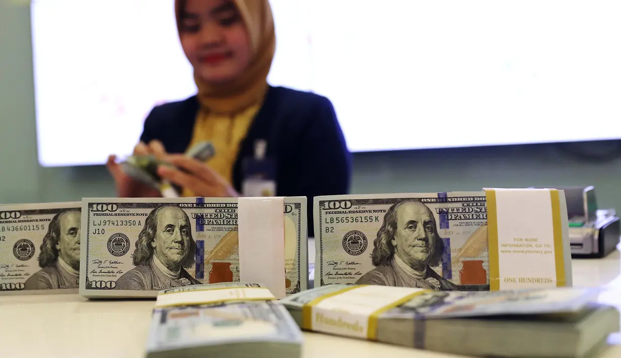 Pekerja bank menghitung uang dollar AS di Jakarta, Jumat (20/10). Pagi ini, Rupiah dibuka di Rp 13.509 per USD atau menguat tipis dibanding penutupan perdagangan sebelumnya di Rp 13.515 per USD. (Liputan6.com/Angga Yuniar)