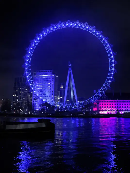 Cahaya biru menerangi objek wisata London Eye untuk berterima kasih kepada National Health Service (NHS) di London, Kamis (7/1/2021). NHS merupakan sistem layanan kesehatan nasional yang menjadi ujung tombak Inggris dalam memerangi pandemi Covid-19. (Tolga Akmen / AFP)