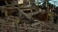 Warga mengamati bangunan yang rusak di Imphal setelah gempa bumi 6,7 SR mengguncang timur laut India, Senin (4/1). Delapan orang tewas sementara lebih dari 100 orang menderita luka-luka akibat gempa. (AFP PHOTO/Dibyangshu Sarkar) 