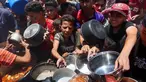 Warga Palestina berusaha mendapatkan makanan di dapur umum yang menyediakan makanan hangat di lingkungan Rimal, kota Gaza pada 18 Juni 2025. (Omar AL-QATTAA/AFP)