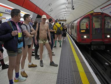 Orang-orang menunggu tube di peron saat mengikuti acara tahunan "No Trousers Tube Ride" di London, Minggu (8/1/2023). No Trousers Tube Ride kembali ke London, pertama kalinya acara tersebut berlangsung sejak Januari 2020. (AP Photo/Kin Cheung)