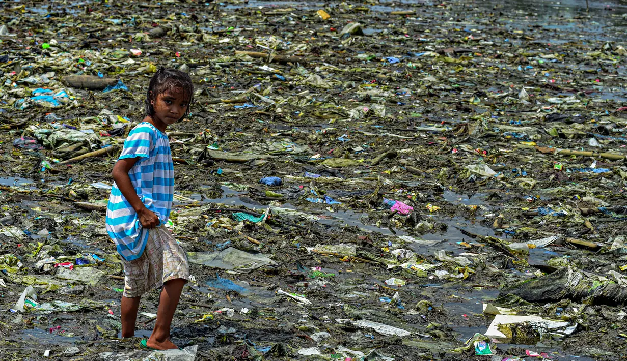 Seorang anak perempuan berjalan di tumpukan sampah di permukiman kumuh di sepanjang garis pantai Pantai Baseco di Manila (28/9/2019). Pada 12 Februari 2002, Presiden Gloria Macapagal Arroyo menyatakan Baseco sebagai tempat tinggal.  (AFP Photo/Maria Tan)