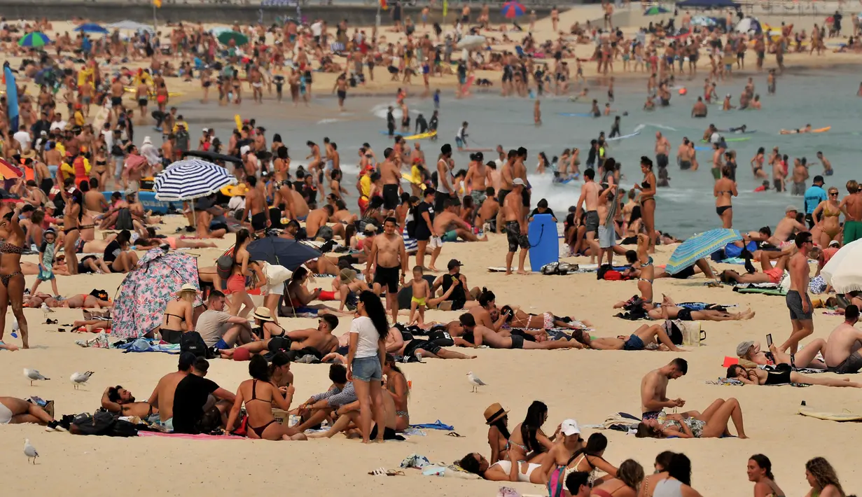 Pengunjung berjemur di pantai Bondi ketika pantai Bondi ketika suhu udara melonjak di Sydney (21/12/2019). Australia terganggu akibat bencana ganda yakni gelombang panas dan kebakaran hutan serta lahan di kawasan tersebut. (AFP/Farooq Khan)
