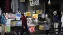 Orang-orang yang mengenakan masker pelindung untuk membantu mengekang penyebaran virus corona berjalan di dekat toko yang menjual masker di Tokyo, Jepang, Rabu (14/10/2020). Tokyo mengonfirmasi lebih dari 170 kasus virus corona baru pada hari Rabu. (AP Photo/Eugene Hoshiko)